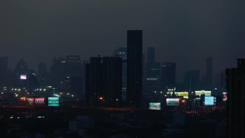 Traffic drives along a highway passing through a foggy downtown at night