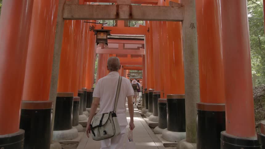 A man carrying bags walks through the asian pergola