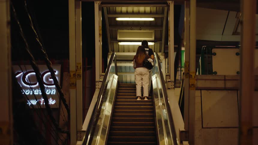 Two women are riding the escalator to the train platform