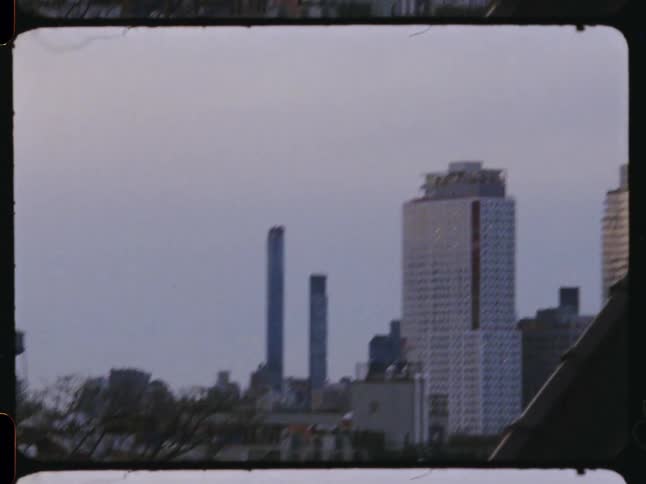 Looking at a bird on a nearby roof before panning left to show a skyscraper