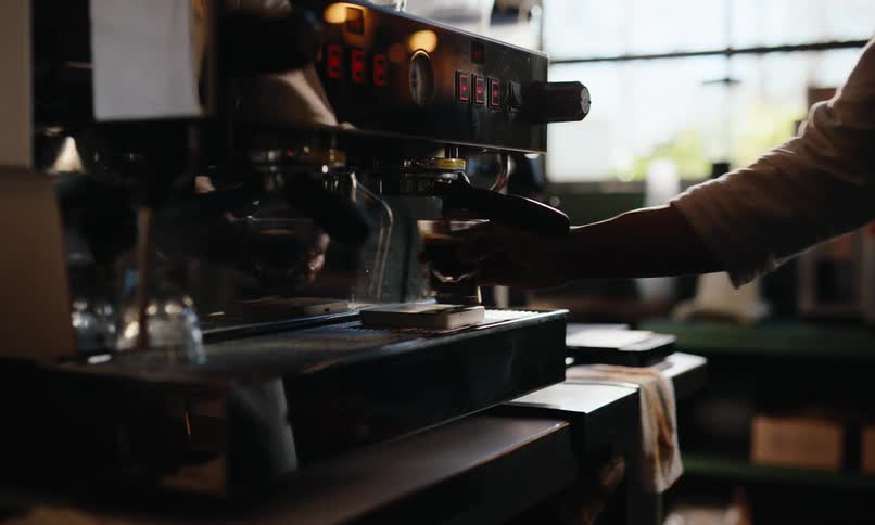 The worker takes a drink from the espresso machine