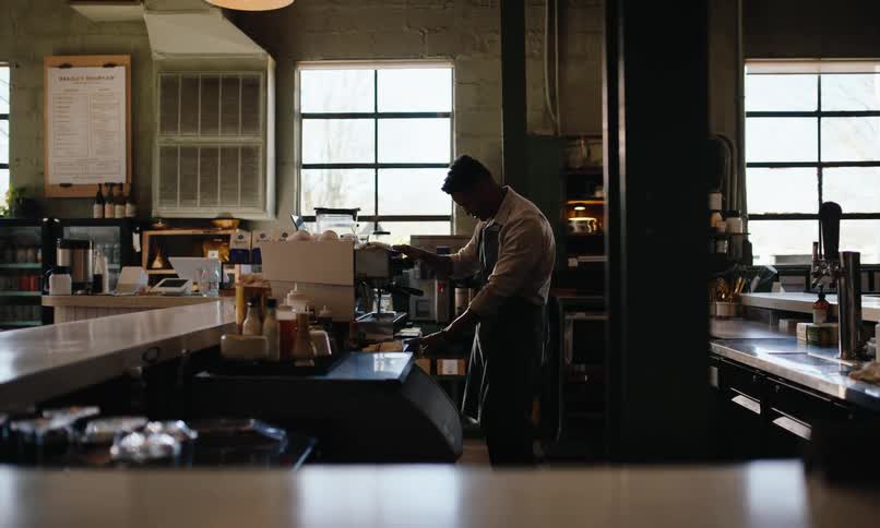Man in apron working in a coffee shop on a machine