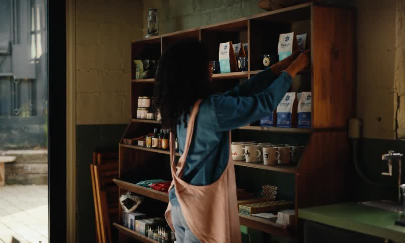 A woman organizes a shelf of merchandise