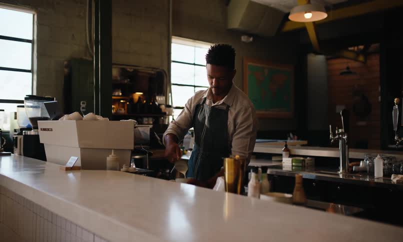 Barista pours milk while standing behind the counter in a coffee shop
