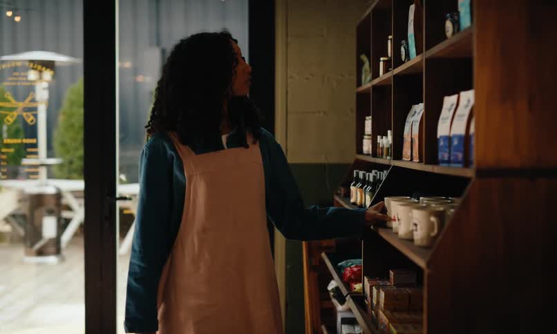Young woman touching up display cabinet in coffee shop
