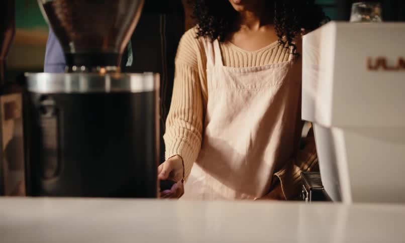 Man shows woman how to use the coffee machine in a cafe