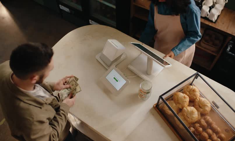 Male customer pays and tips at the counter of a coffee shop