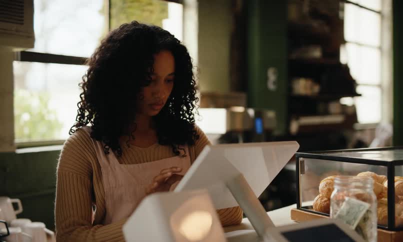 Cashier interacting with a tablet at a coffee shop checkout