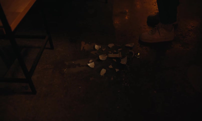 A waiter holding a tray stands by a table with three customers turning to look down at a shattered cup on the floor
