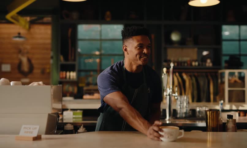 A man behind the counter serves coffee to a customer