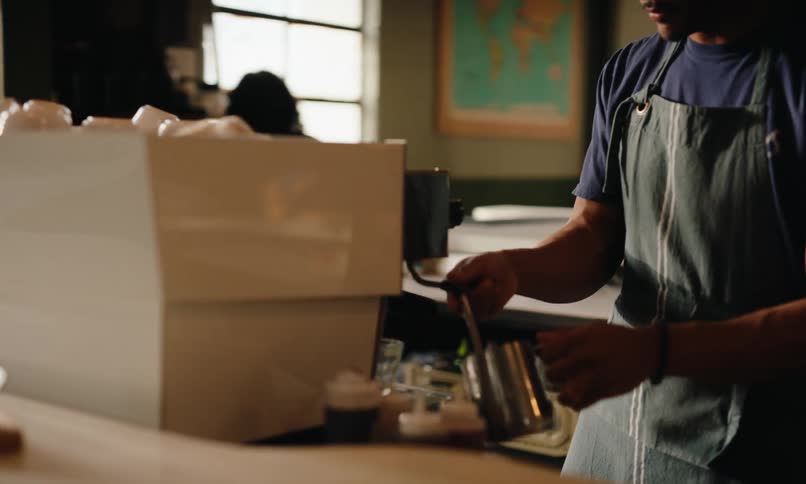 Man in apron working on a coffee machine in a coffee shop