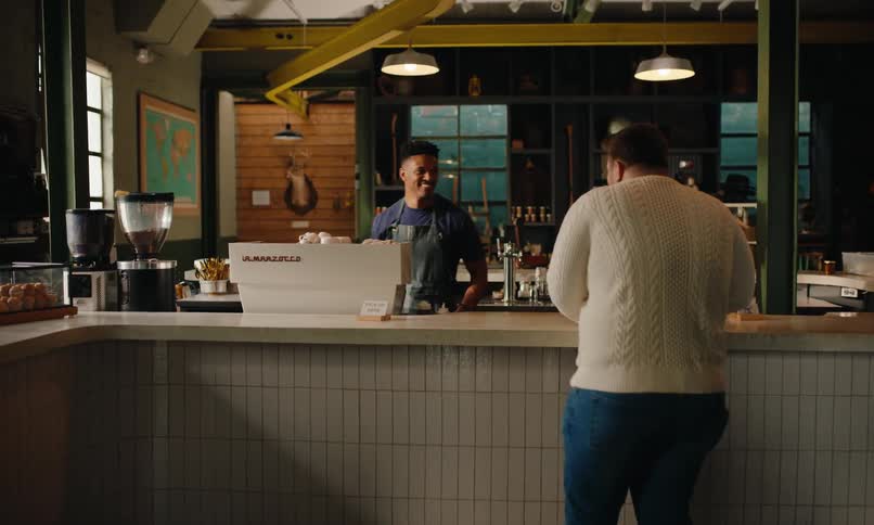 Customer reaching for a cup of coffee at the counter of a coffee shop