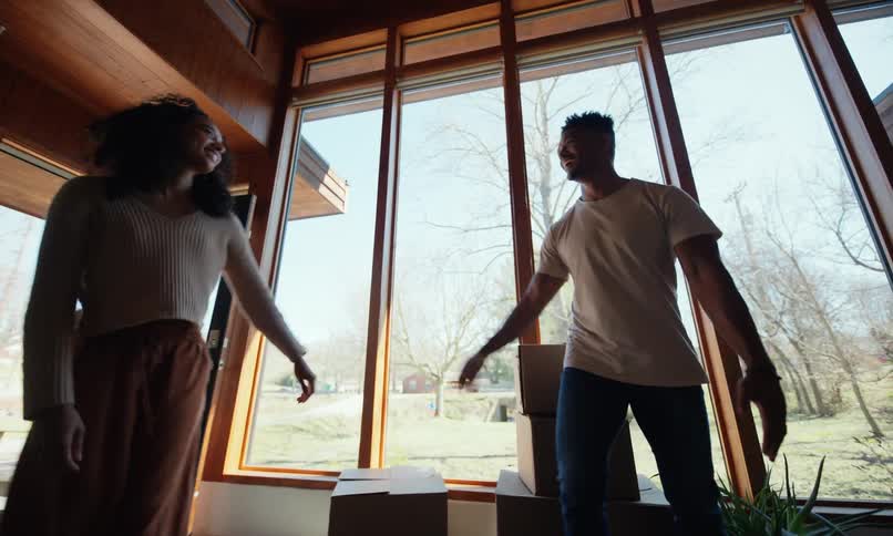 A man and woman set down their boxes and embrace celebrating their move into a modern home
