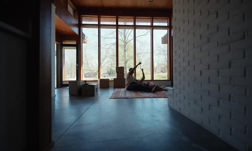 A woman is laying in a mans lap as he sits on the floor and the point upward