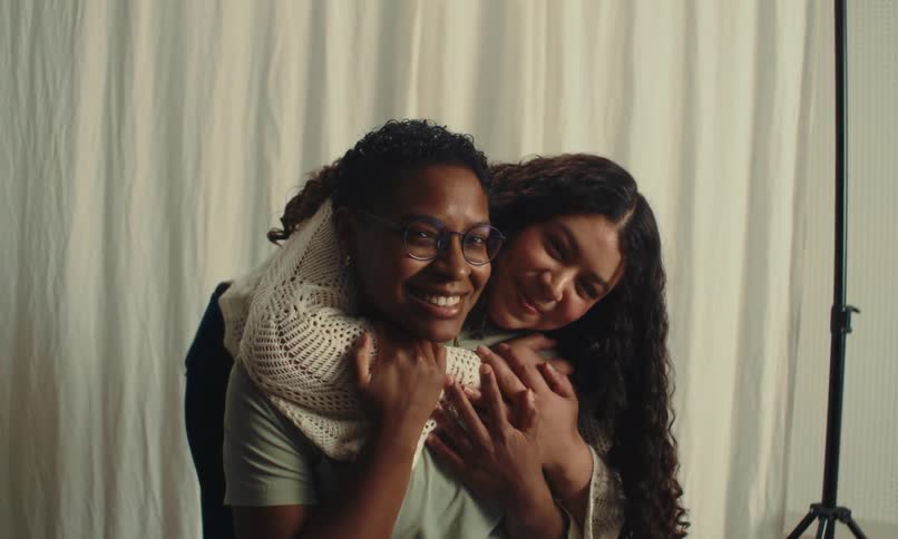 Two friends pose and smile while hugging