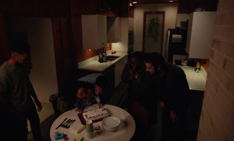 A group of people are celebrating a small childs birthday with a cake