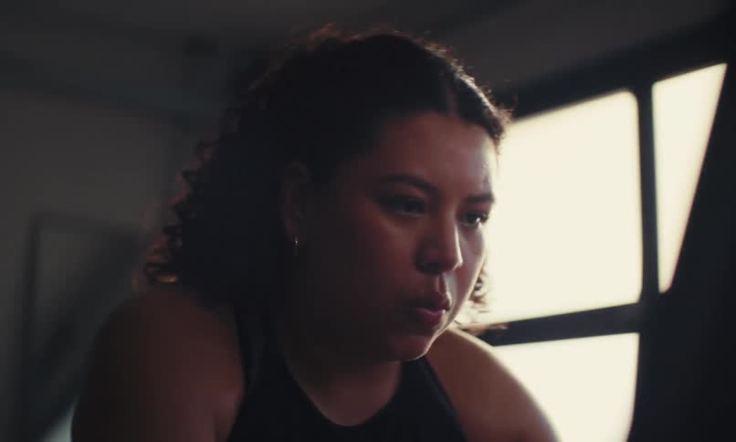 A woman is pedaling fast on the exercise bike