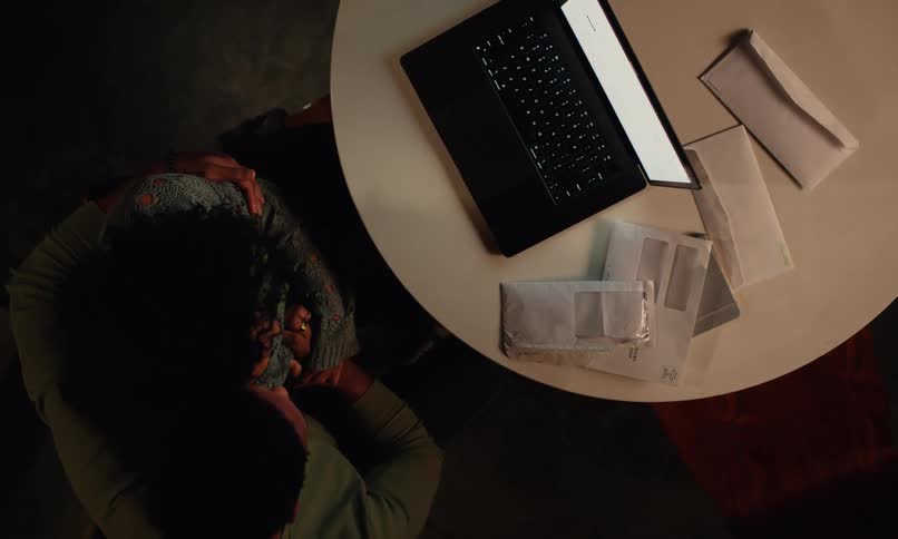 A man warmly embraces his partner consoling her as they focus on a laptop in the soft warm light of the room