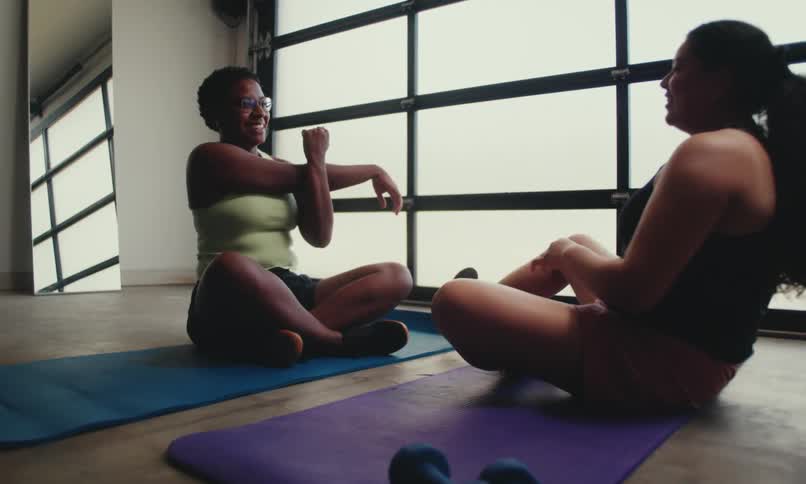 Two women are stretching in the gym