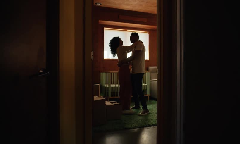 Happy young couple slow dancing in a room near a crib