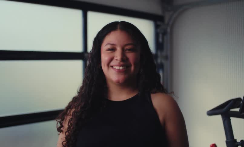 Black curly haired woman in an indoor space and smiling