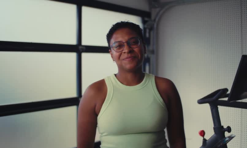 A black woman laughs and smiles while standing in a workout room