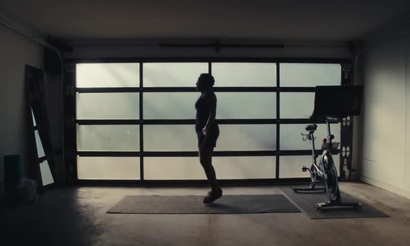 A woman is jumping rope in the dark gym
