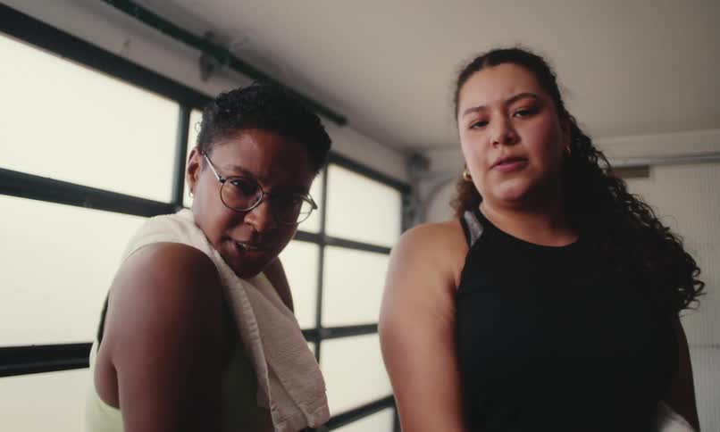 Two women flex and talk in the gym