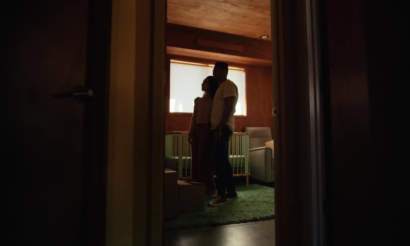 Man and woman in a room with a crib watching