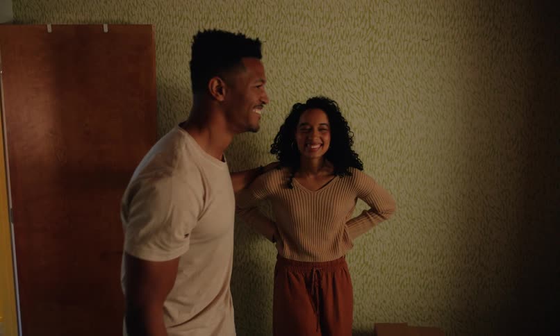 Happy couple carrying boxes walking into room then standing over an empty crib