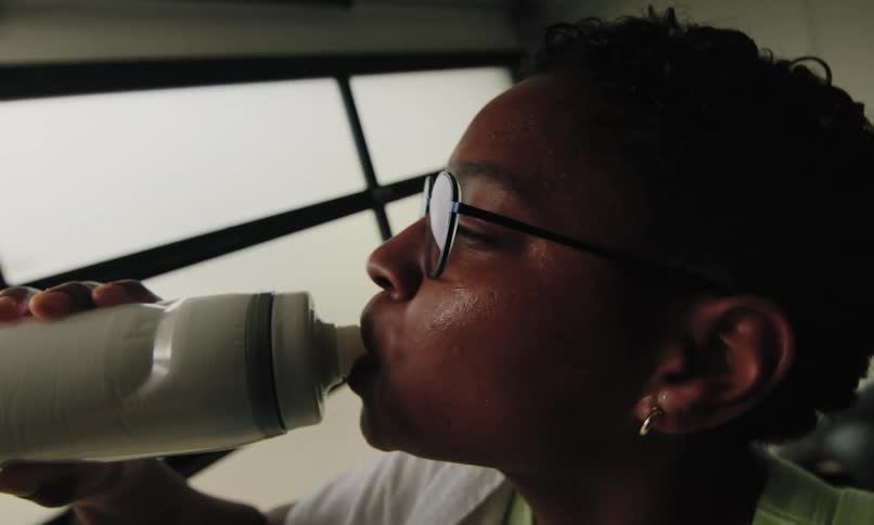 A sweating women drinks from her water bottle