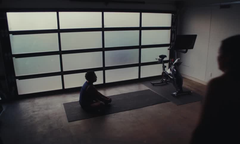 A woman is stretching on a mat when another woman comes in and helps her get up