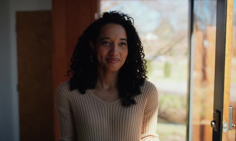 A footage of a lady smiling and holding some books
