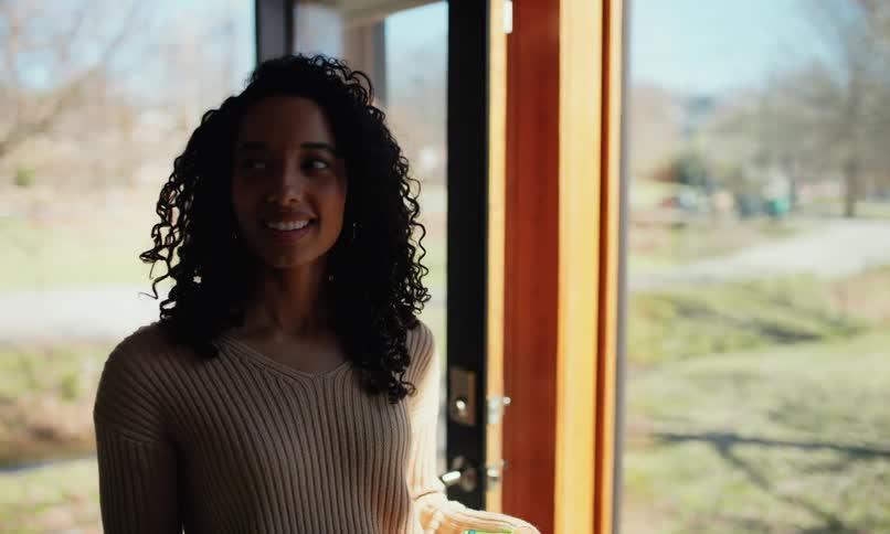 Woman smiles when walking into her stream side home with her spouse