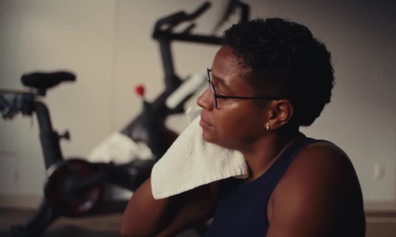 A woman uses a towel to clean sweat off her face