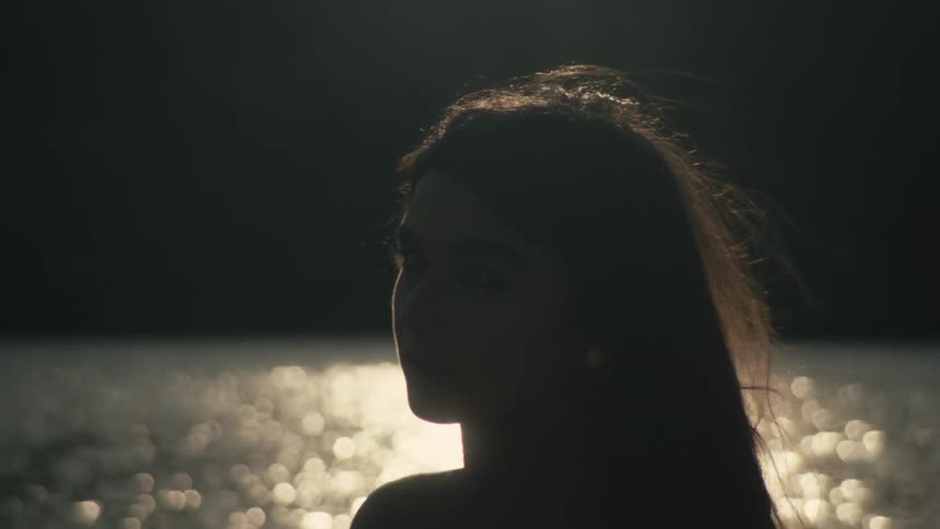 The wind blows the womans hair by the water