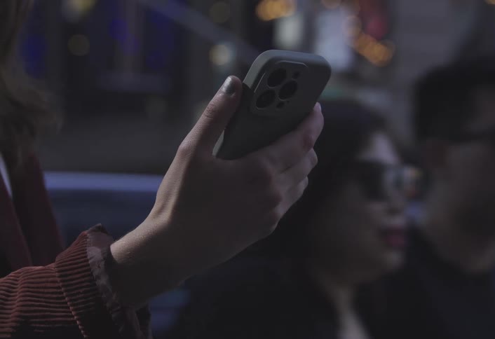 A womans hand holds a smartphone on a busy metropolitan street