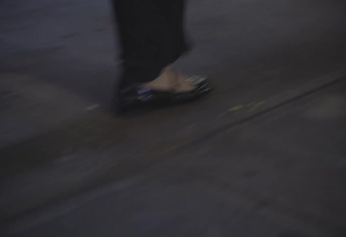 Woman wearing dress shoes and slacks walks across the sidewalk