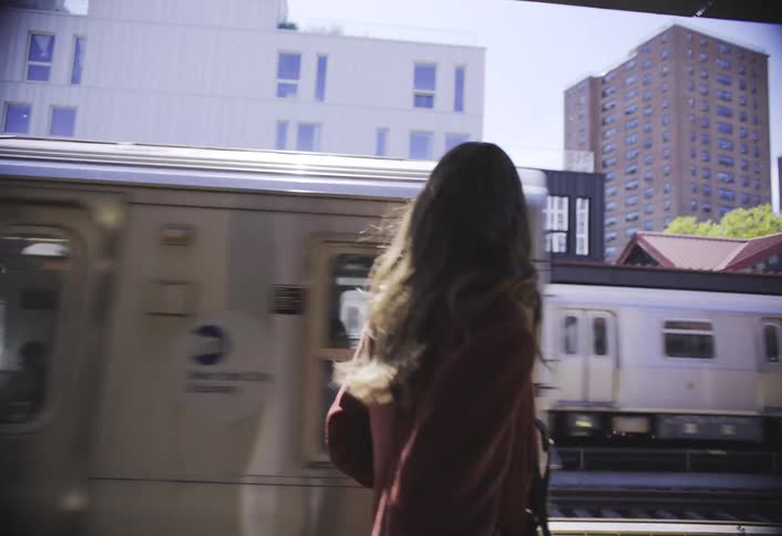 Woman walking at a station with a train passing by