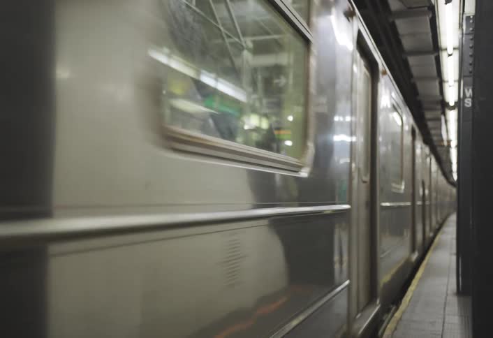 Silver train passing through a subway station
