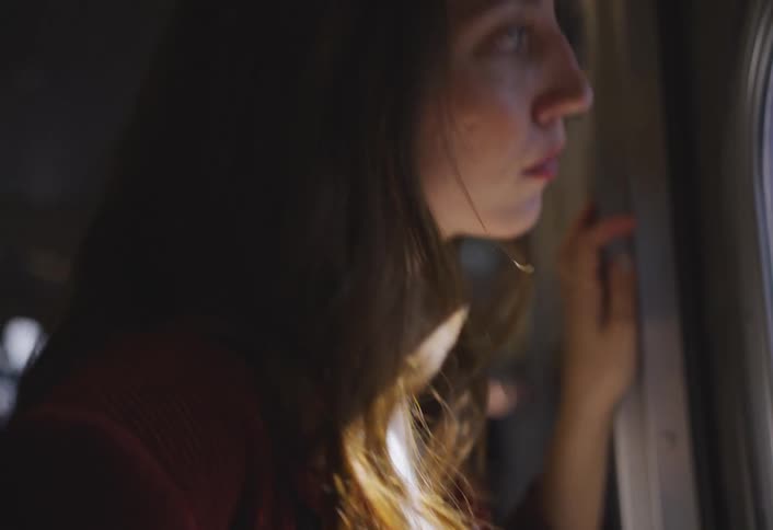 Woman standing and looking out the door window of a train during the daysighs
