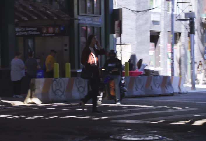 A woman is walking down a city street as traffic drives by