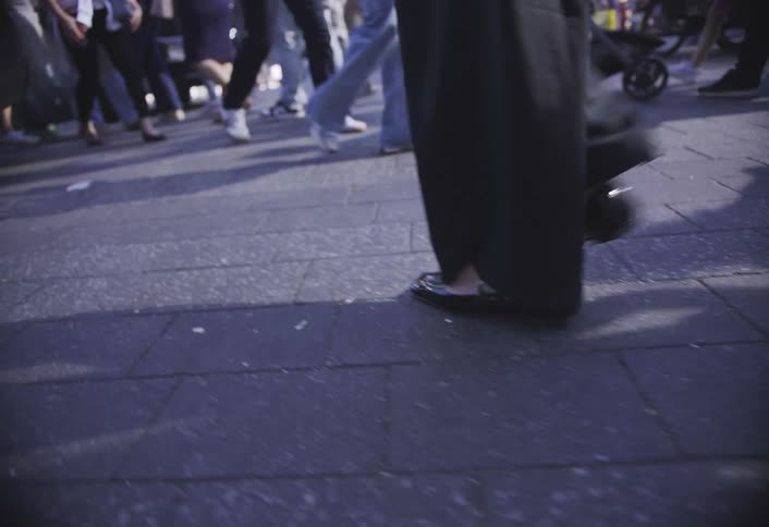 Closeup of legs walking briskly on a busy city sidewalk