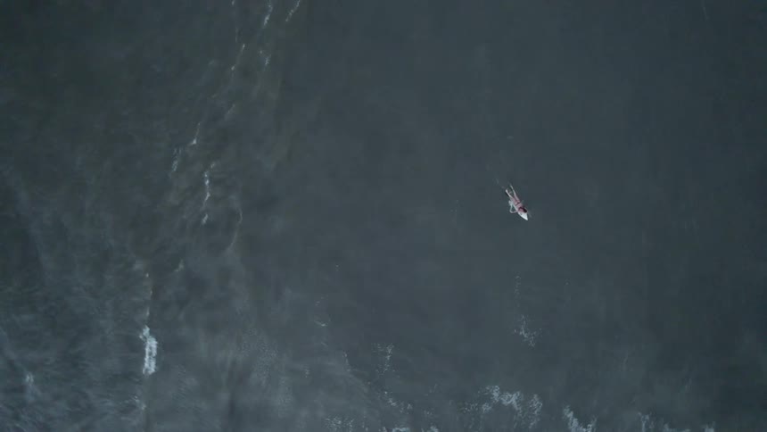 A person is swimming on their surfboard
