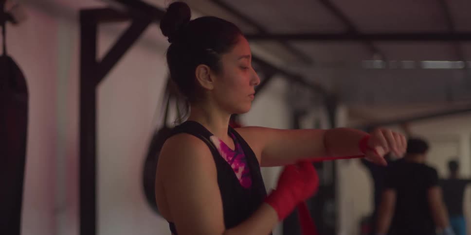 Woman in a gym wrapping a tape around her wrist
