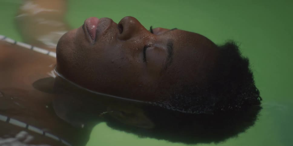 A woman slowly swims as she floats on her back in a pool