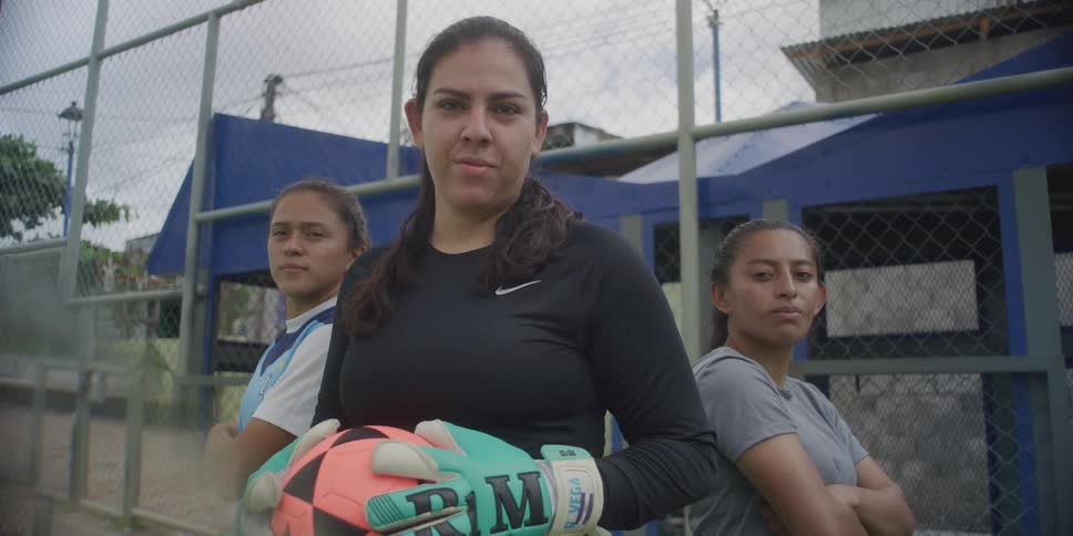 Women are on a field and one is holding a soccer ball