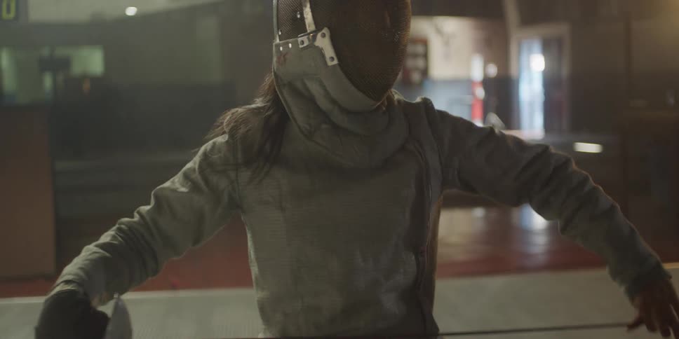 A person removes a cover from a thin fencing sword and flexes the sword