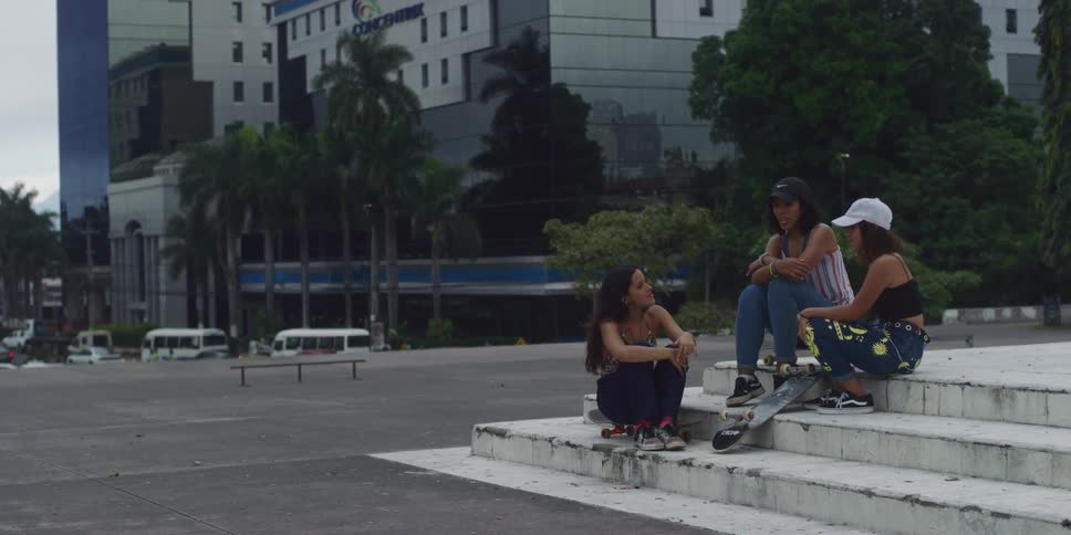 Three women are sitting on some steps in a downtown area of the city
