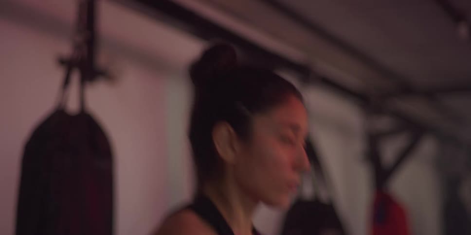 A young woman in the gym wearing gloves is doing jumping jacks jumping and twisting her arms